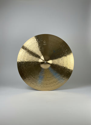 Round metallic object with concentric circles on a dark textured background